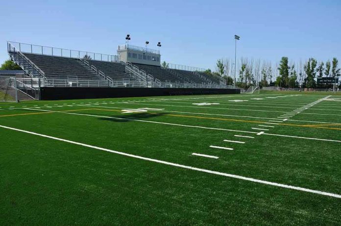 55132081 Empty football field with bleachers in background