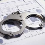 Handcuffs on fingerprint form with fingerprints visible.
