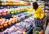 Woman in a yellow coat shopping for fruits in a supermarket
