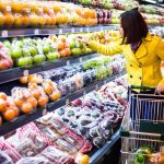 Woman in a yellow coat shopping for fruits in a supermarket