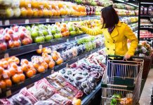 Woman in a yellow coat shopping for fruits in a supermarket