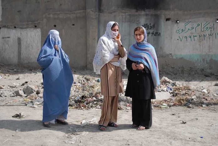 shutterstock_13492072.jpg Three women in traditional attire standing in an urban setting with debris in the background