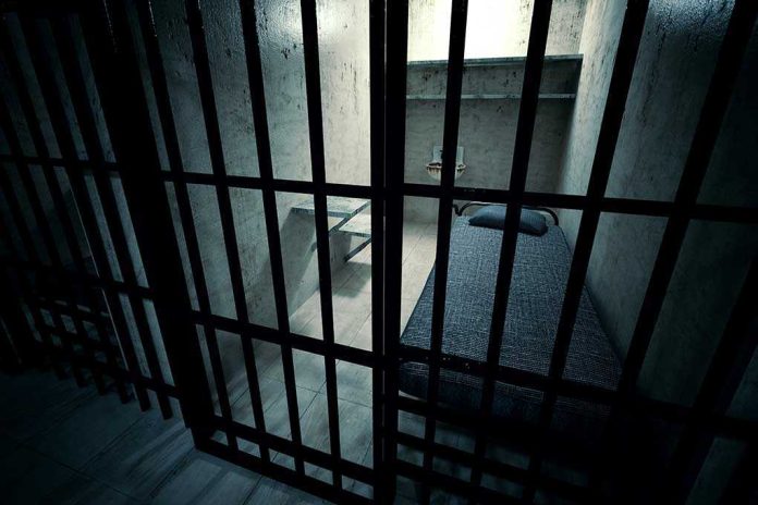 shutterstock_138714137.jpg Interior view of a prison cell with a bed and metal bars