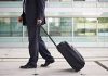 A businessman in a suit walking with a suitcase at an airport