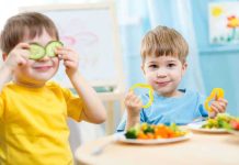 Two children playing with vegetables while enjoying a meal