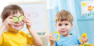 Two children playing with vegetables while enjoying a meal
