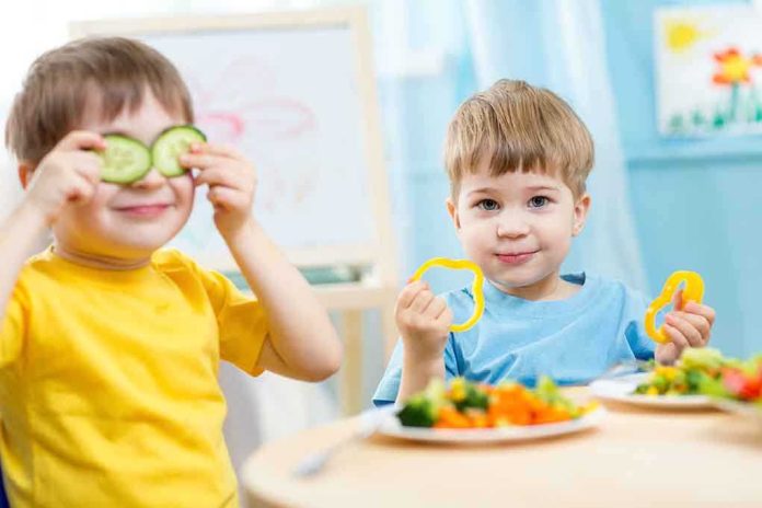 Two children playing with vegetables while enjoying a meal