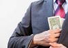 Person in suit putting money in jacket pocket