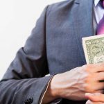 Person in suit putting money in jacket pocket