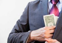 Person in suit putting money in jacket pocket