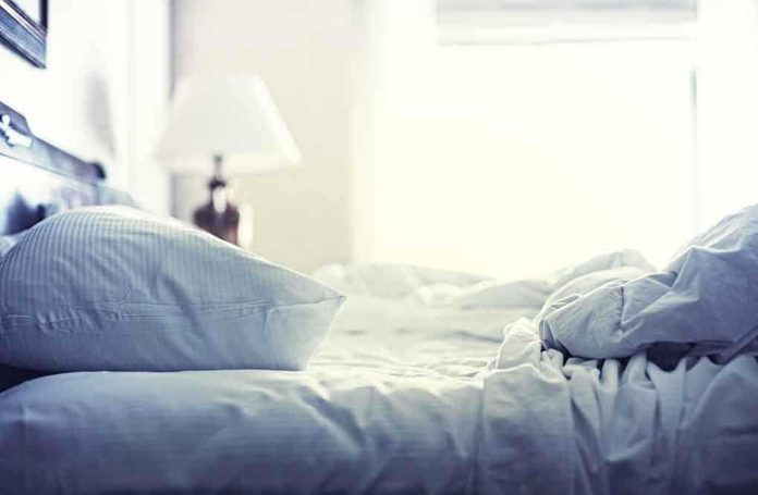 A cozy unmade bed with soft pillows and bedding in a well lit room