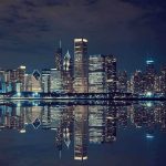 Nighttime view of a city skyline with reflections on water
