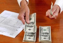 Hands counting cash and reviewing financial documents on a wooden table
