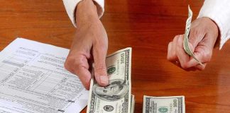 Hands counting cash and reviewing financial documents on a wooden table