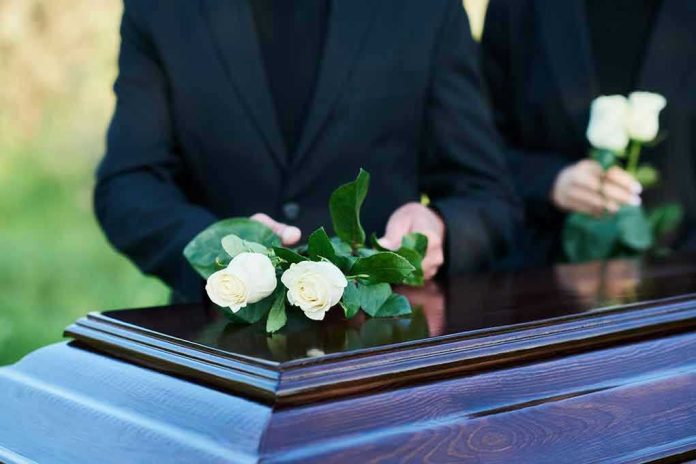 2360876213 People placing white roses on a casket