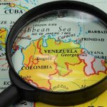 Magnifying glass focusing on Venezuela and Colombia on map