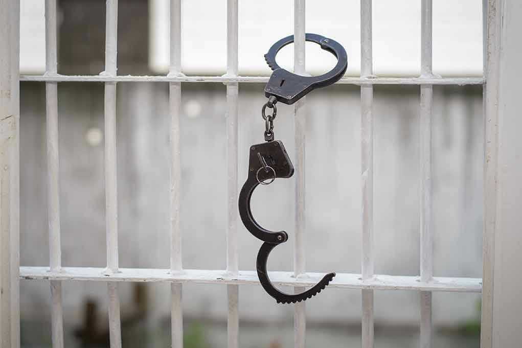 Handcuffs hanging on white metal bars