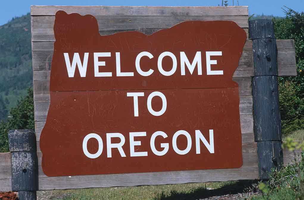 Welcome sign to Oregon with a brown background and white text