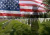 A military cemetery with white gravestones and an American flag overlay featuring a soldier silhouette
