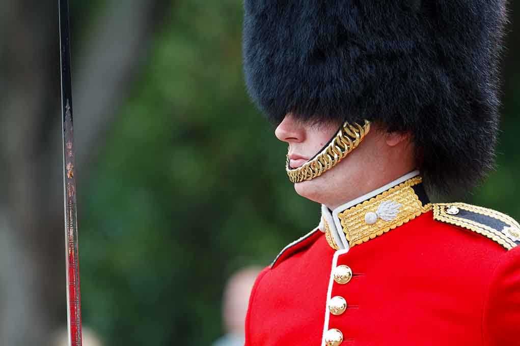 British soldier in ceremonial uniform with a black fur hat standing guard