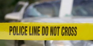 Yellow police tape reading POLICE LINE DO NOT CROSS in front of a vehicle