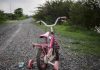 Failed Suicide Attempt Saves 5 Kids Pink childrens bike with training wheels on gravel path.