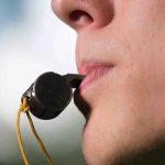 Whistle Alert System Rattles Trump’s ICE Plans Person holding a whistle in their mouth.