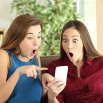 Two women look surprised at a phone