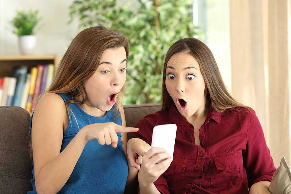 Two women look surprised at a phone
