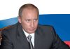 A serious looking man in a suit sitting at a table with a Russian flag in the background