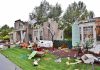Houses with significant storm damage and debris scattered around the yard