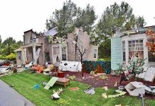 Houses with significant storm damage and debris scattered around the yard