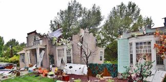 Houses with significant storm damage and debris scattered around the yard