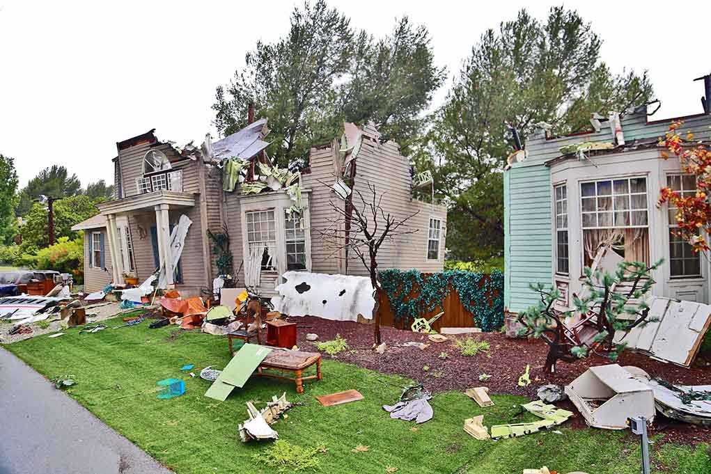 Houses with significant storm damage and debris scattered around the yard