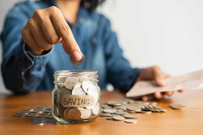 shutterstock_1523822675.jpg Person placing a coin into a savings jar labeled 'SAVINGS'