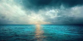 A serene ocean view with a dramatic sky and sunset reflection on the water