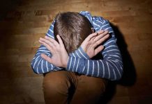 A child sitting on the floor with their hands covering their face, expressing distress