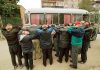 Group of men with hands on their heads near a bus during a police operation