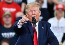 Man in suit pointing, speaking at a rally.