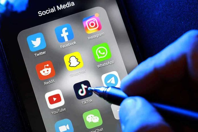 1907235274 Social media apps on phone screen with hand holding stylus.