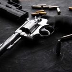 Campus Horror: Brown Shooting Leaves 2 Dead Revolvers and bullets on a dark surface.