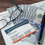 Rural Rescue Cash Vanishes Into Washington Black Box Medicare card glasses pen money on wooden table