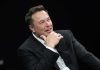 Elon Musk’s Bold Move — Internet Revolution Man in suit smiling, resting chin on hand.