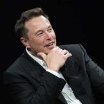 Elon Musk’s Bold Move — Internet Revolution Man in suit smiling, resting chin on hand.