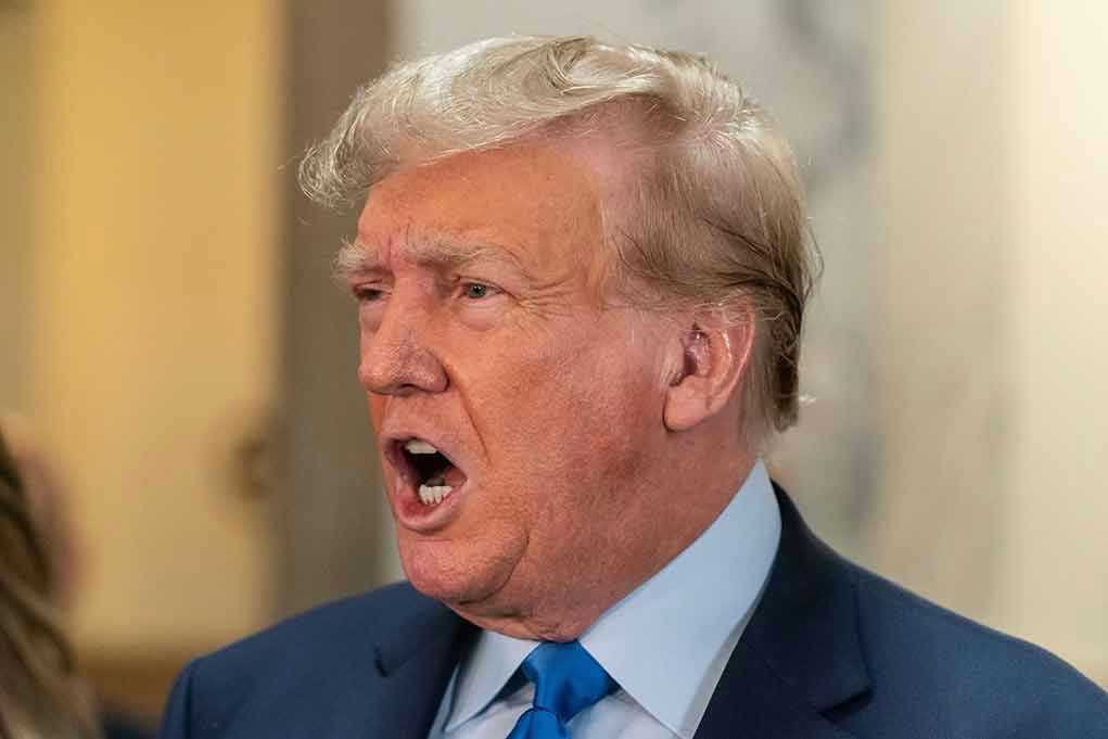 Man in suit with open mouth, speaking passionately.