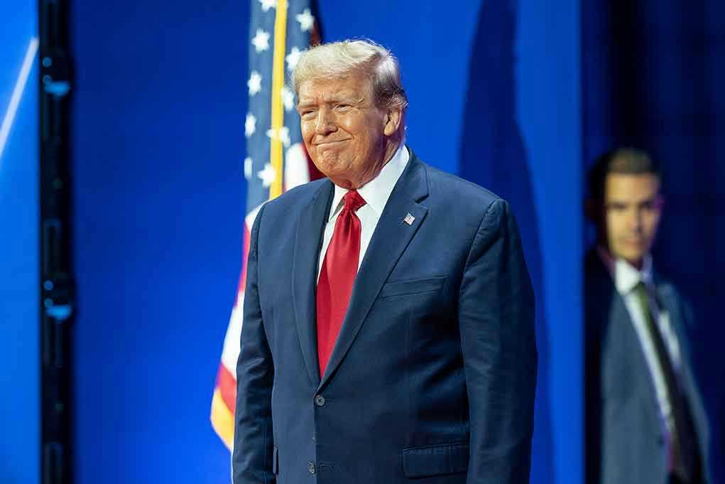 Man in suit next to American flag.