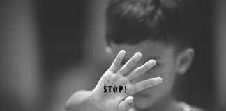 Child holding up hand with STOP! written on palm.