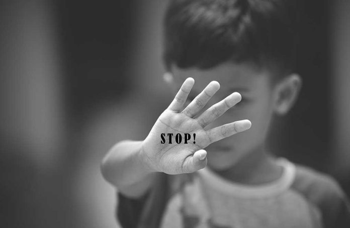 Child holding up hand with STOP! written on palm.