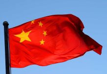 Communist Takeover Plot EXPOSED! Chinese flag waving against a clear blue sky