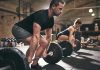 The ODD Health Benefit of Cursing Man and woman lifting barbells in gym.